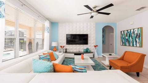 Chill out in style! This living room features a comfy couch, a mounted TV for movie marathons, and a ceiling fan to keep you cool.