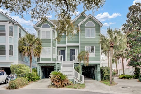 Coastal-style home with elevated design featuring tropical landscaping and convenient parking beneath the property.