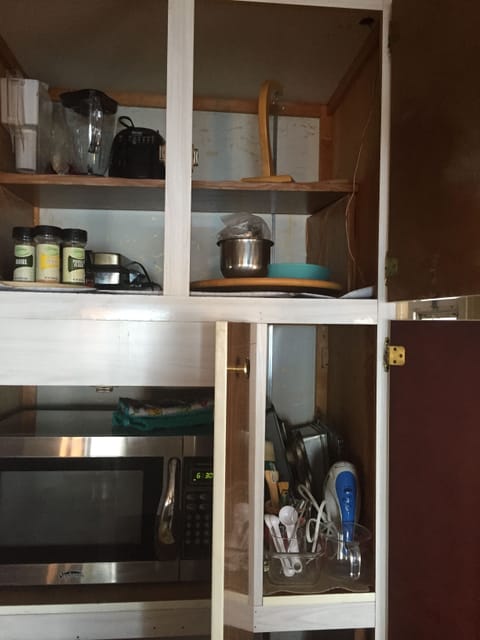 By the hidden microwave is blender, popcorn popper, a baking cupboard.