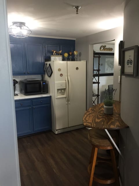Another angle of the kitchen showing the refrigerator, microwave, and bar area.