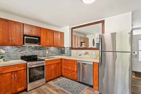 A fully updated kitchen featuring warm wood cabinetry, stainless steel appliances, and a stylish tiled backsplash.