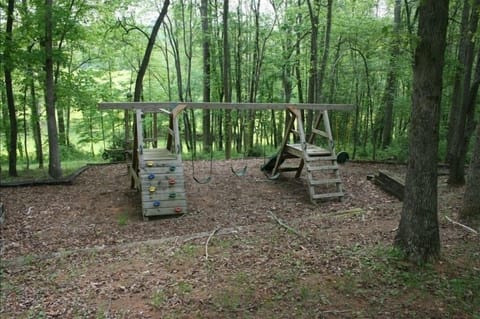 Relax on the porch while you watch your children play on this wooden playground.