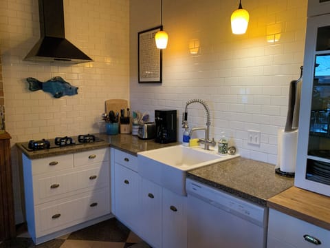 Stovetop, farmhouse sink, dishwasher, and glass-front cabinets in the kitchen
