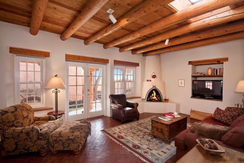 Spacious living area has kiva fireplace, grand Vigas, and Santa Fe blue sky