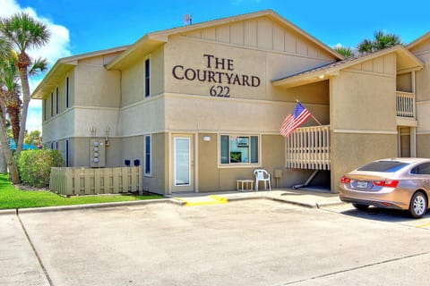 The Courtyard 622 welcomes guests with convenient covered parking and tropical palm trees under bright blue skies.