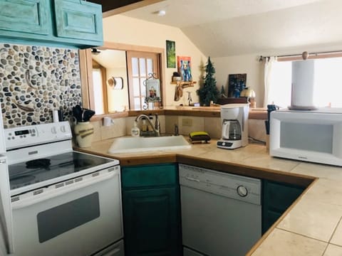 Kitchen area with bar has full fridge, microwave, coffee maker, dishwasher
