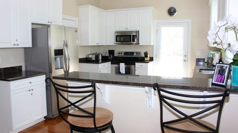 The kitchen features granite counters, custom cabinetry, and seating for 2.