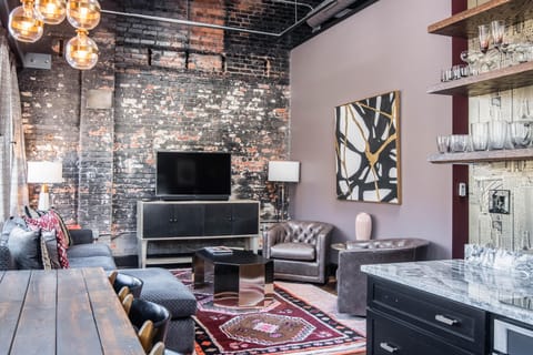 Relax in the sunlit living room, where exposed brick walls meet vintage furnishings for a cozy, urban retreat.
