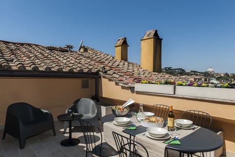 The terrace over the roofs. In the background Saint Peter's dome. Eat out table 