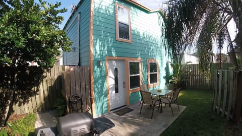 Patio with table, chairs, shade umbrella, grill and hose to rinse off the sand 