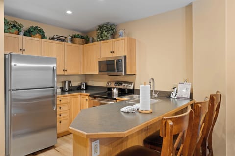 Full kitchen with stainless steel appliances and breakfast bar with seating for 3