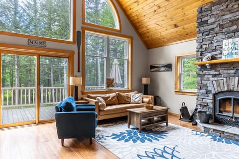 Living room with floor to ceiling stone fireplace (wood not provided). Comfortable leather couch, Roku TV, fast Starlink WIFI, huge windows overlooking the lake.