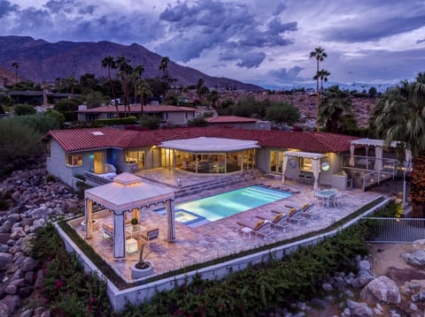 Twilight aerial of rear terrace and poolside cabana seating area.