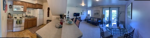 Pano of the fully stocked kitchen, living and dining room overlooking the patio.