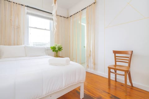 Bright, airy bedroom with crisp white linens, hardwood floors, and soft natural light—clean, serene, and thoughtfully styled.

