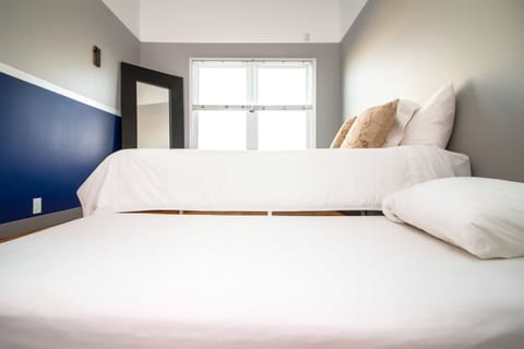 Bright, modern bedroom with crisp white linens, plush pillows, and natural light—clean, calming, and perfect for a restful stay.

