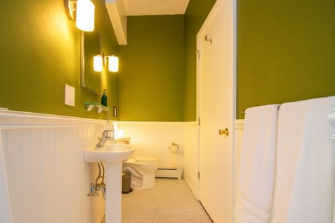 Clean, well-lit bathroom with fresh green walls, classic tile, and modern fixtures—bright, functional, and inviting.
