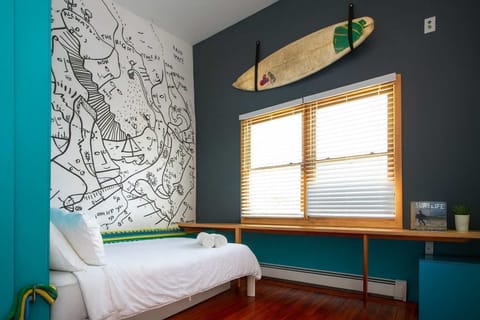 Stylish bedroom with surf-inspired decor, custom wall art, and cozy bed—creative, modern, and full of local character.
