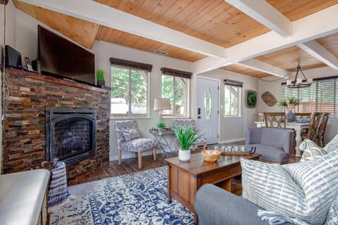Living room features a stone fireplace with a mounted TV, patterned armchairs, and a blue patterned rug.