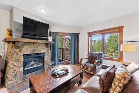 Cozy up by your stone fireplace while mountain views frame your comfortable living space through panoramic windows.