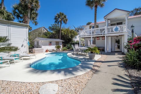 Your private oasis awaits with a sparkling pool surrounded by swaying palms and tropical landscaping in this charming coastal retreat.