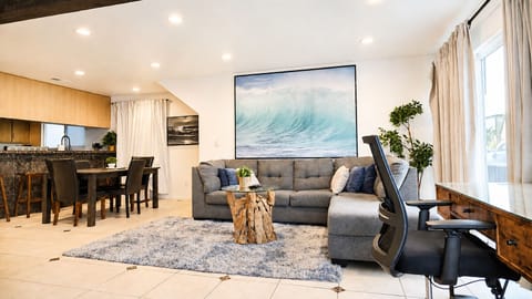 Living room with large L-shaped couch, comfortable work desk, and 4K Flatscreen