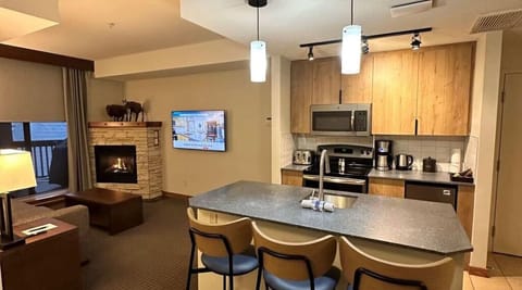 Inviting kitchen and living area with warm wood tones and a cozy fireplace, creating a welcoming atmosphere.