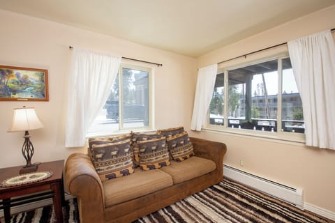 Settle into your cozy corner living room, where soft natural light filters through white curtains and rustic charm meets modern comfort.