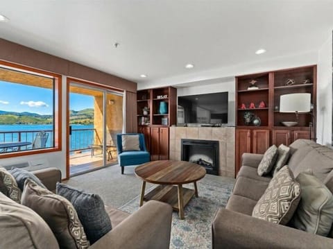 Unwind in your elegant lakeside living room where plush seating surrounds a warm fireplace, while stunning water views flow through floor-to-ceiling windows.
