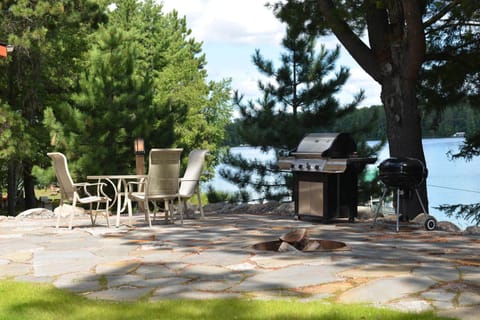 Terrace area on the lake side of the cottage with grills, fire pit, and settee