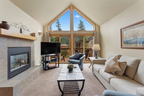 Unwind in your bright living room where vaulted ceilings and floor-to-ceiling windows frame forest views, complete with cozy fireplace.