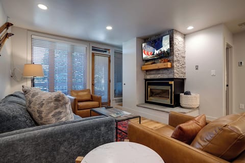 Unwind in your stylish living space featuring leather seating, a stone fireplace, and flatscreen TV for cozy evenings.