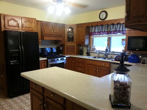Kitchen stocked with plates, cups, silverware, pots & pans.