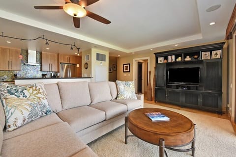 Open-concept living room with large windows, ceiling fan, and comfortable seating.