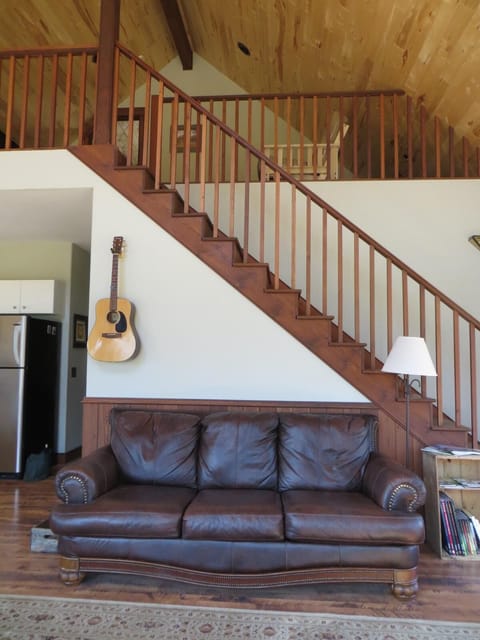 House guitar in living room. Stairs to loft area with futon and tv.