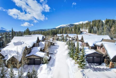 The stunning architecture of this mountain lodge is accentuated by fresh snow and a clear blue sky, providing a cozy ambiance in a picturesque setting.