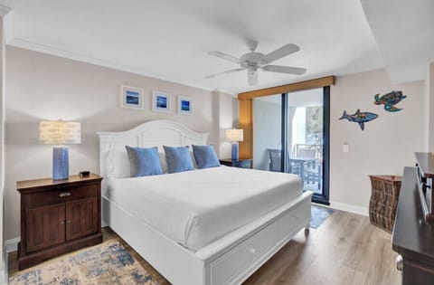 Sink into crisp white linens with ocean-blue accents in your peaceful bedroom sanctuary, complete with balcony access and coastal charm.