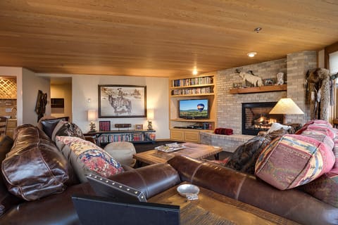 Sink into plush leather seating by your crackling fireplace, surrounded by rustic charm and entertainment for cozy evenings.