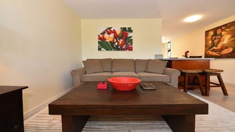 Cozy living space featuring a plush sofa, tropical artwork, and a sleek wooden coffee table for a relaxing island vibe