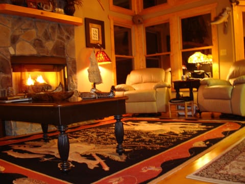 Great room at night, leather sofa, recliners, vaulted ceiling, fireplace, big TV