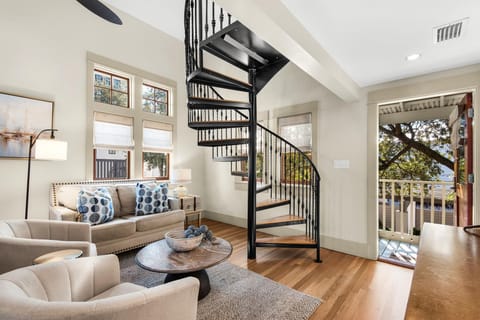 Sunlit living room with cozy seating and spiral staircase