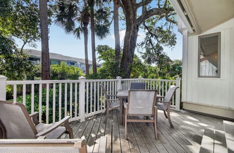 Your private deck welcomes you with comfortable seating surrounded by lush palms and oaks, perfect for morning coffee or peaceful evenings under the coastal canopy.