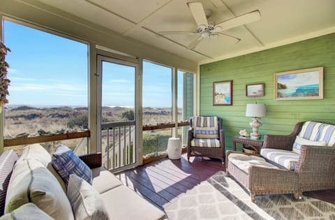 Your sunlit screened porch invites you to relax in coastal comfort, watching nature unfold across the peaceful landscape.