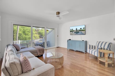 Unwind in your bright living space with comfortable seating, entertainment center, and peaceful balcony views of lush greenery.