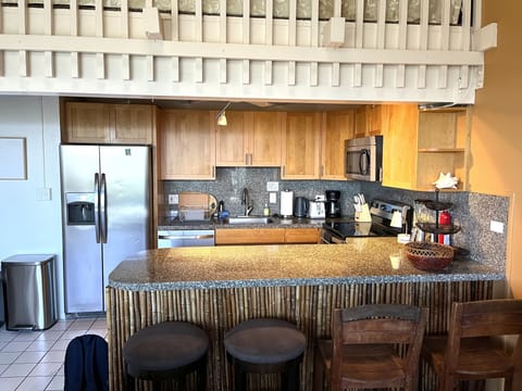 Kitchen area with chairs for sitting at the bar.