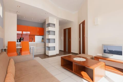 A view of the living and dining areas, with bright orange accents, including chairs and the kitchen backsplash, creating a vibrant and modern interior design.
