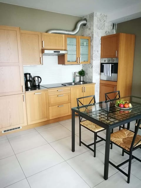A modern kitchenette with light wooden cabinets, black countertop, and plenty of storage space, designed for functionality and style.