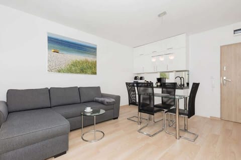 Modern and atmospheric living room with grey double sofa bed, glass dining table with black chairs and coffee table.