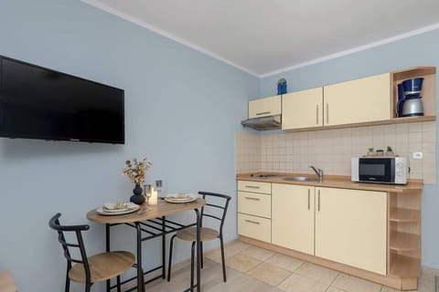 The living space features a small table with chairs, creating a spot for dining or working. A large TV hangs on the wall for entertainment.