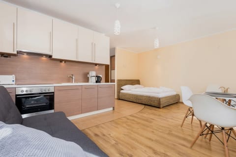 A modern kitchen with sleek cabinets and a built-in stove. There is an adjacent dining table with chairs for casual meals.